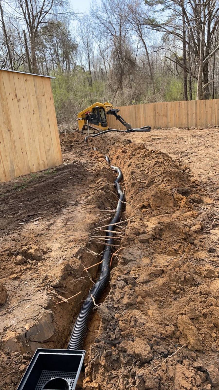 Drainage trench with pipe being installed in a yard