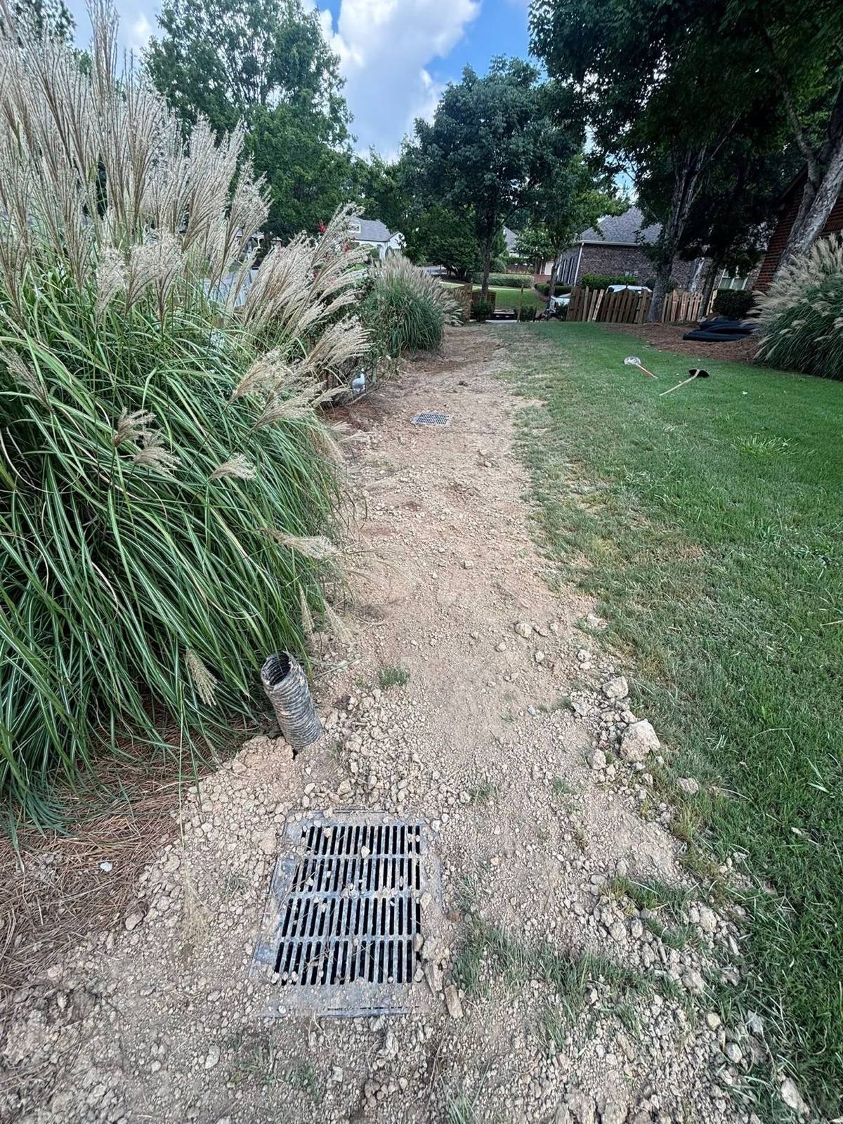Gravel drainage swale with a catch basin grate in a residential yard